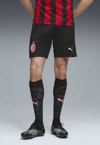 Sort og rød mønstrede fodboldtrøje med sorte shorts. Sorte sokker med camouflage design og ordet "MILAN" i rød. Støvlerne er sorte med grønne detaljer.