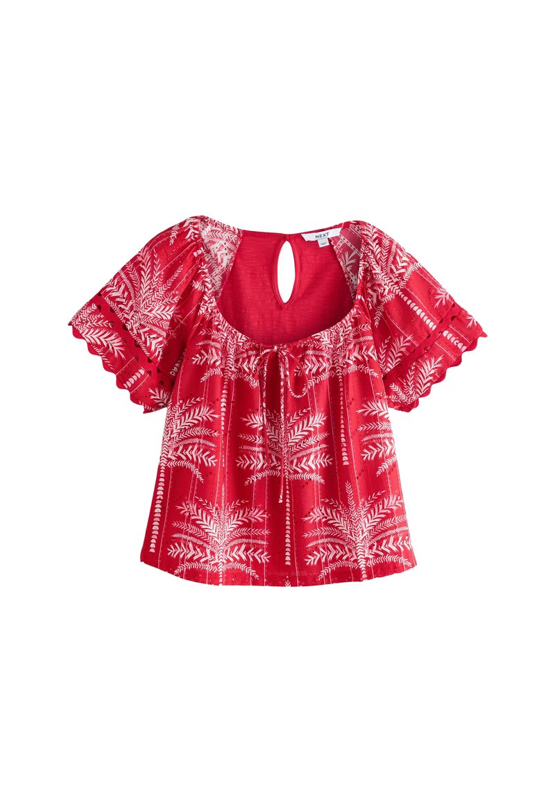 Blouse rouge à manches courtes avec encolure arrondie, détail à lacer et motif de feuilles blanches sur l'ensemble. Présente une découpe en forme de clé à l'arrière.