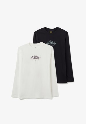 Twee T-shirts met lange mouwen, één wit en één zwart, gemaakt van katoen. Beide hebben een gestileerde grafische print op de borst.
