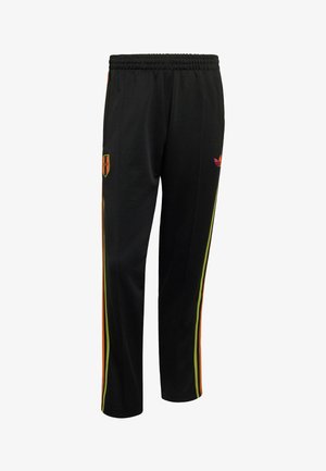 Pantalon de sport noir avec des bandes latérales orange et jaune, taille élastique, et petit logo rouge et orange sur la cuisse gauche.