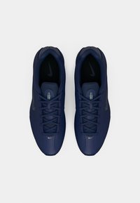 Granatowe buty sportowe z teksturowaną siateczką, wyściełanym kołnierzem i kontrastowym czarnym logo Nike w kształcie łyżwy. Sznurowadła w standardowej konfiguracji.