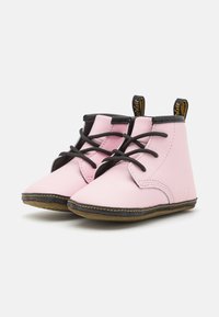 Rosa läderankelboots med svarta snören och sömmar. Rundad tå och robusta bruna gummisålar. Inkluderar svart hälpulltab.