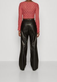 Red lace cropped long-sleeve top paired with high-waisted black leather wide-leg pants, showcasing a smooth texture and fitted silhouette.