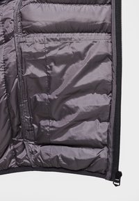 Wnętrze szarej kurtki puchowej z pikowaną teksturą, kieszenią na zamek i czarną lamówką. Miękka, gładka tkanina o lekko błyszczącym wykończeniu.