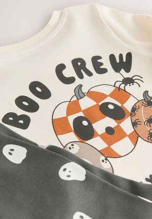 Puuvillane dressipluus kreemikal taustal, millel on oranži ja valget ruudulist kõrvitsat, koomikslikke kummitusi ning tekst "BOO CREW". Halli varrukate detail.
