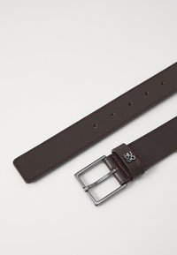 Barna bőröv sima felülettel, téglalap alakú ezüst csat és piros varrási részletek. Több állítási lyukkal rendelkezik.