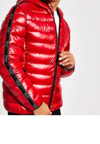 Veste rembourrée rouge avec une finition brillante, dotée d'une capuche, d'une fermeture éclair et de rayures latérales noires avec texte de logo. Conçue pour la chaleur et le confort.