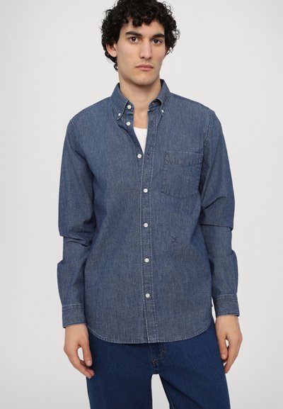 Camicia in denim blu scuro con colletto classico, tasca frontale e maniche lunghe. Presenta una trama sottile e bottoni bianchi.