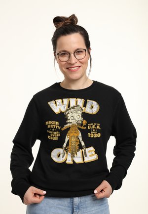 Czarna bluza z kapturem z vintage'owym nadrukiem postaci na motocyklu. Napis "WILD ONE" w pogrubionych białych i żółtych literach.