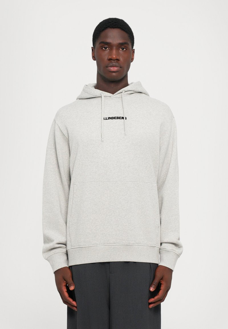 Hoodie gri deschis dintr-un material moale, cu o buzunar frontal, glugă ajustabilă cu șnur și un logo negru pe piept.
