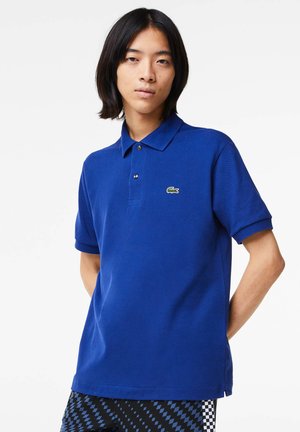 Polo blu realizzato in tessuto texturizzato, con colletto, maniche corte e un piccolo logo verde ricamato sul petto.