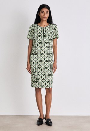 Kurzärmliges Kleid in Hellgrün mit schwarzen geometrischen Mustern. Gerader Schnitt, knielang, mit rundem Ausschnitt und einfachen vorderen Knöpfen.