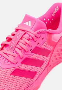 Scarpa sportiva rosa con tomaia in mesh, dettagli testurizzati e suola in gomma. Presenta lacci e il logo a tre strisce sul lato.