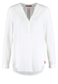 Blouse blanche à manches longues avec col en V, patte à trois boutons, col rond et ourlet incurvé, présentée sur un fond uni.