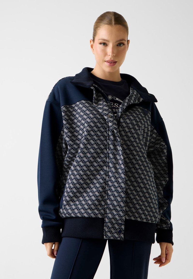 Marineblauwe pulloverjas met patroon op het voorpand, ritssluiting en geribbelde boorden. Voorzien van een kraag en details in contrasterende kleuren.