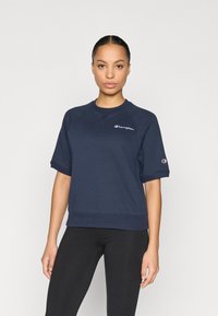 Μπλούζα από βαμβάκι σε ναυτικό μπλε με κοντά μανίκια, ριμπ τελείωμα και λογότυπο στο αριστερό στήθος. Διαθέτει άνετη εφαρμογή και στρογγυλή λαιμόκοψη.