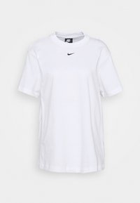 T-shirt bianco in cotone con maniche corte e scollatura tonda. Presenta un piccolo logo nero di Nike sulla parte superiore del petto. Design essenziale, vestibilità rilassata.