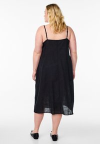 Abito midi in lino nero con spalline regolabili e vestibilità ampia, caratterizzato da un delicato motivo testurizzato e orlo arrotondato.