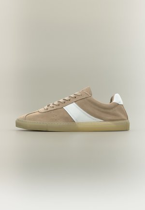 Beige ruskind lavtop sneaker med hvid diagonal stribe, hvid hælflap, beige snørebånd og gennemsigtig beige gummisål på neutral baggrund.