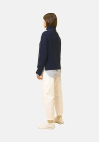 Granatowy sweter z golfem, nałożony na jasnoniebieską koszulę w pasy, połączony z luźnymi białymi spodniami i kremowymi sneakersami.