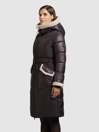 Pikowana kurtka w ciemnobrązowym kolorze z kapturem wyłożonym sztucznym futrem i ozdobą. Posiada pasek w talii oraz dwie przednie kieszenie. Gładka tekstura i długość do kolan.
