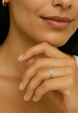 Gros plan sur la partie inférieure du visage d’une femme et sa main montrant la couleur naturelle des lèvres et une bague en argent à son doigt.