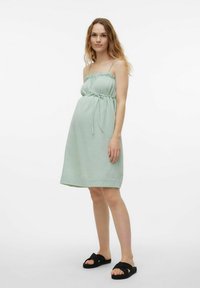 Jasnozielona sukienka do kolan, wykonana z teksturowanej tkaniny. Posiada cienkie ramiączka, marszczoną górę i pasek do samodzielnego zawiązania w talii.