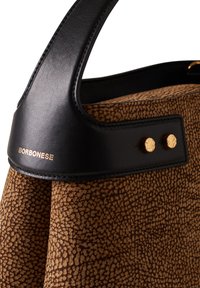 Brun tekstureret stof taske med et sort læderhåndtag, der har guldfarvet hardware og logoet "BORBONESSE" præget på stroppen.
