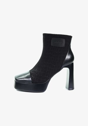 Czarne botki na wysokim obcasie z platformą, skórzanymi palcami i obcasami, elastyczną tkaniną na górze oraz wytłoczonym prostokątnym logo z boku.