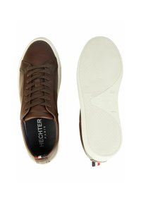 Bruine leren sneaker met witte zool, veters gestrikt, merknaam "Hechter Paris" aan de binnenkant, en maat 42 gemarkeerd op de zool.