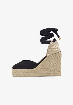 Espadrille compensée en toile noire avec plateforme en jute tissé et brides à nouer à la cheville en tissu noir assorti.
