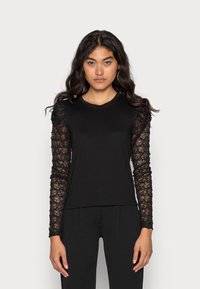 Camisola preta de manga longa com tecido liso no corpo e mangas de renda transparente com padrões florais e acabamentos texturizados.