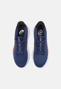 Scarpe sportive blu con tomaia in rete testurizzata, accenti neri, dettagli arancioni, logo rotondo sulla linguetta e colletto imbottito.
