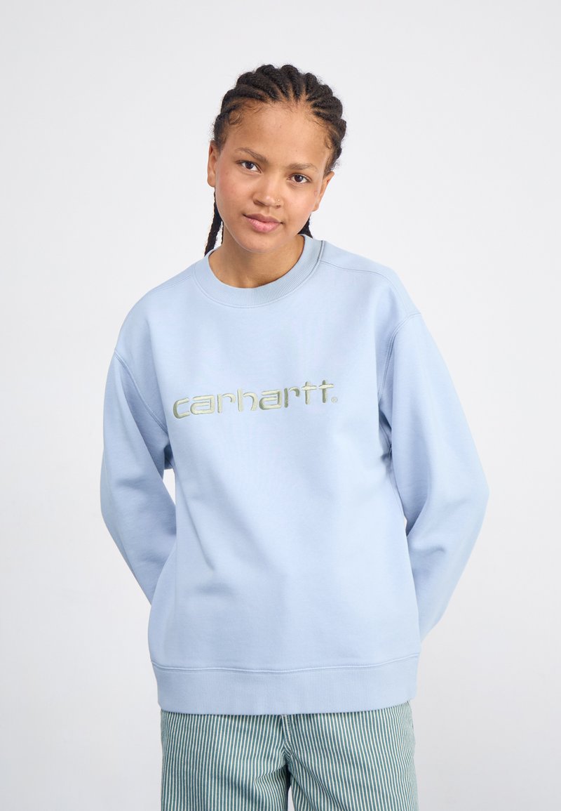 Lyseblå hettegenser med ribbestrikket krage og mansjetter, med et fremtredende brodert "carhartt."-logo i en kontrastfarge.