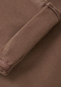 Primer plano de tela marrón con una superficie texturizada que presenta costuras visibles y un detalle estructurado y acolchado en el lado.