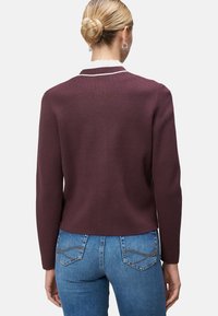 Maroon knit cardigan with a round neckline, long sleeves, and a fitted design. Features a contrasting white trim at the collar.