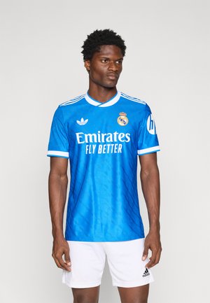 Blaues Fußballtrikot mit weißen Akzenten, mit dem Text "Emirates Fly Better", dem Real Madrid-Logo und gestickten Streifen an den Ärmeln.