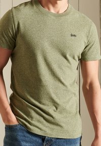 Olivgrünes T-Shirt aus Baumwollmischung mit kurzen Ärmeln, Rundhalsausschnitt und subtiler Struktur; mit einem kleinen, gestickten Logo auf der Brust.