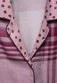 Camisa de botones en color burdeos y rosa con lunares, un cuello y un patrón a rayas. Está confeccionada con una tela ligera y cuenta con una textura suave.