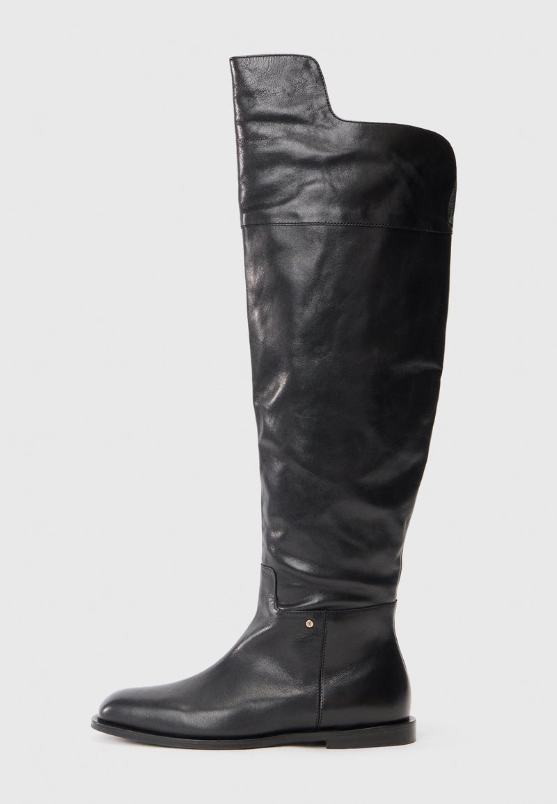 Zwarte leren kniehoge laars met platte zool en een iets bredere bovenkant met een asymmetrische snit aan de buitenkant.