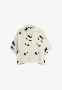 Camisa de manga corta color crema con siluetas de pájaros negros en un patrón disperso, confeccionada en un tejido suave y con frente abotonado.