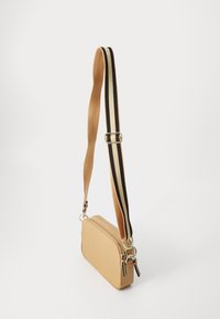 Borsa a tracolla color beige con forma rettangolare, dotata di una tracolla spessa a righe in nero e beige. Chiusura con cerniera e dettagli in hardware argentato.