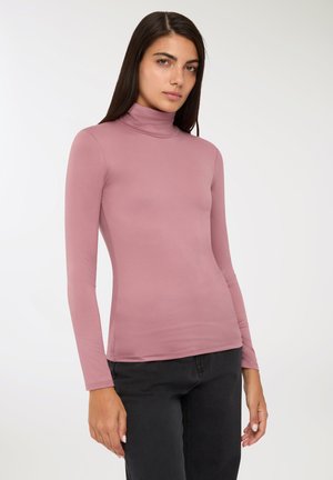 Maglietta a collo alto rosa chiaro realizzata in un tessuto elasticizzato e liscio; presenta maniche lunghe e un design aderente, abbinata a pantaloni neri.