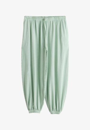 Losse lichtgroene trainingsbroeken met elastische taille en enkelsluiting en een aantrekkoord in de taille, getoond op een witte achtergrond.
