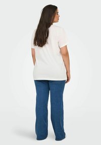 Lysfarvet bomulds t-shirt med korte ærmer, parret med blå splitbukser. Glat tekstur, afslappet design og løs pasform.