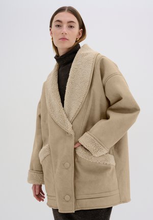Beige coat with a textured, shearling collar and trim. Features large buttons and side pockets, designed in a loose, oversized fit.
