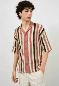 Camiseta de punto de manga corta con rayas verticales en rosa, blanco y verde, con botones en la parte delantera y cuello. Diseño texturizado y de corte relajado.