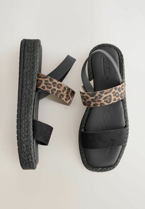 Čierne sandále s tkanou podrážkou. Vrchná časť obsahuje dva popruhy: jeden z látky s leopardím vzorom a druhý z čierneho nazúvacieho semišu.