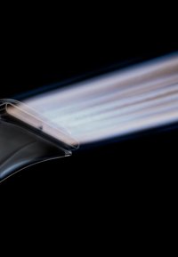 Elektrischer Haarglätter erhitzt sich mit leuchtenden Keramikplatten vor schwarzem Hintergrund.