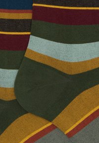 Calzini a righe in tonalità di verde, marrone, bordeaux, blu e giallo, caratterizzati da una texture morbida e motivi diagonali. Dettaglio della punta arrotondata visibile.